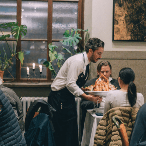 Servitör serverar gäster i lilla matsalen